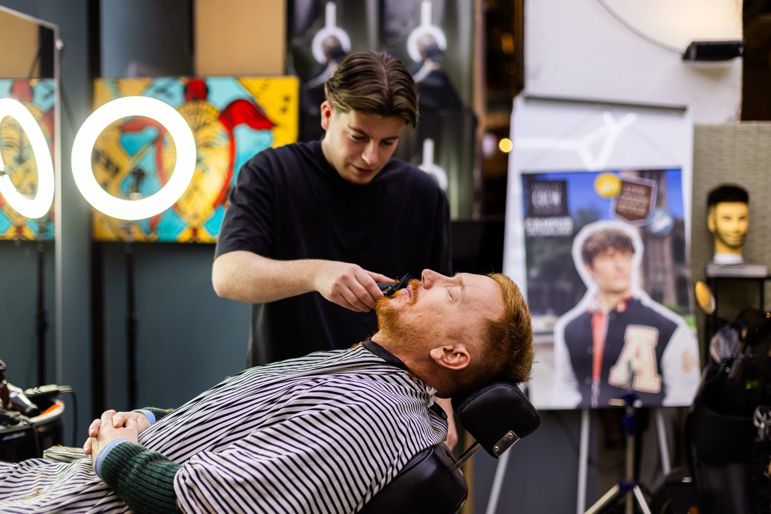 Barbier zet de baardlijn scherp bij een klant die achteroverligt in de barberstoel